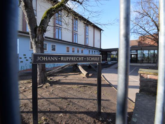 Ein Schild mit der Aufschrift „Johann-Rupprecht-Schule“ steht auf einem Schulhof