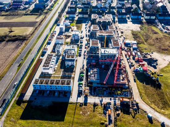 Eine Drohnenaufnahme zeigt das Baugebiet Neue Stadtmitte in Rheinstetten. Erste Häuser sind bereits fertig, andere befinden sich in der Entstehung. Auf der Baustelle stehen ein großer Kran und Baucontainer. 