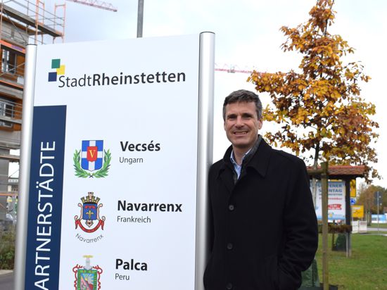 Rheinstettens Oberbürgermeister Sebastian Schrempp steht an einen Straßenschild.