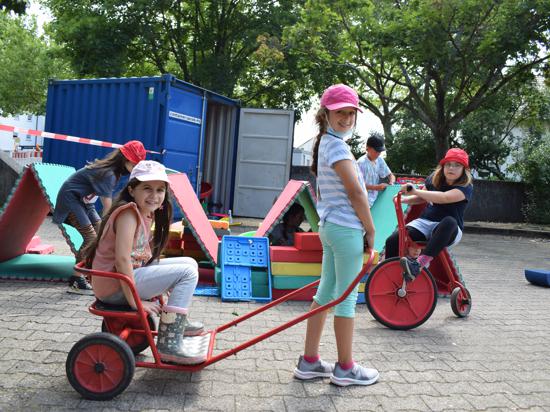 Mit der Rikscha über den Schulhof: Zwei Mädchen haben sichtlich Spaß bei der Stadtranderholung in Rheinstetten.
