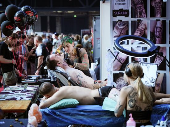 Armelle Vhen vom Death Ray Studio aus Nottingham (Großbritannien) tätowiert während der 31. Tattoo Convention in der Arena Berlin einen jungen Mann am Hals. 