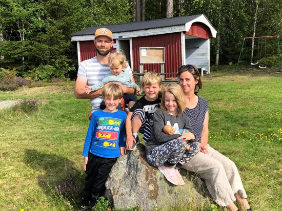 Eien Familie sitzt in Schweden vor einer Schwedenhütte. 
