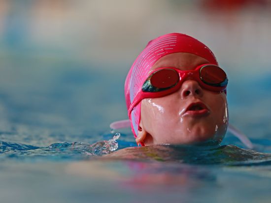 Ein Mädchen schwimmt während der Prüfung zum "Seepferdchen" im Schwimmbecken. 