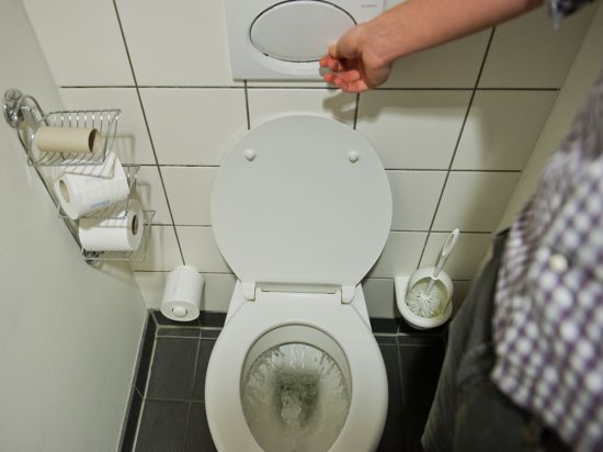 Ein Mann betätigt eine Toilettenspülung. 