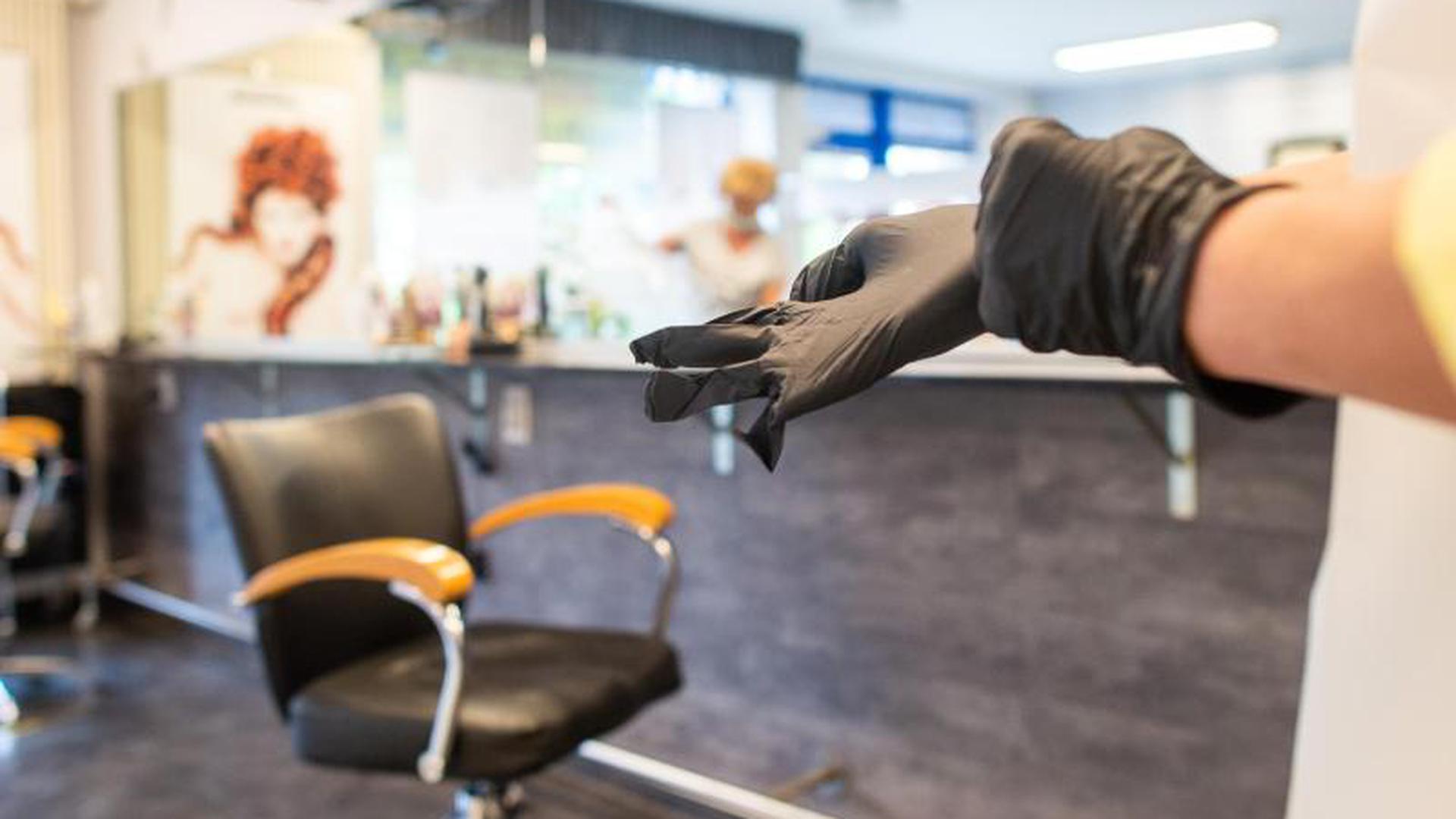 Eine Friseurmeisterin zieht sich Handschuhe zum Schutz an