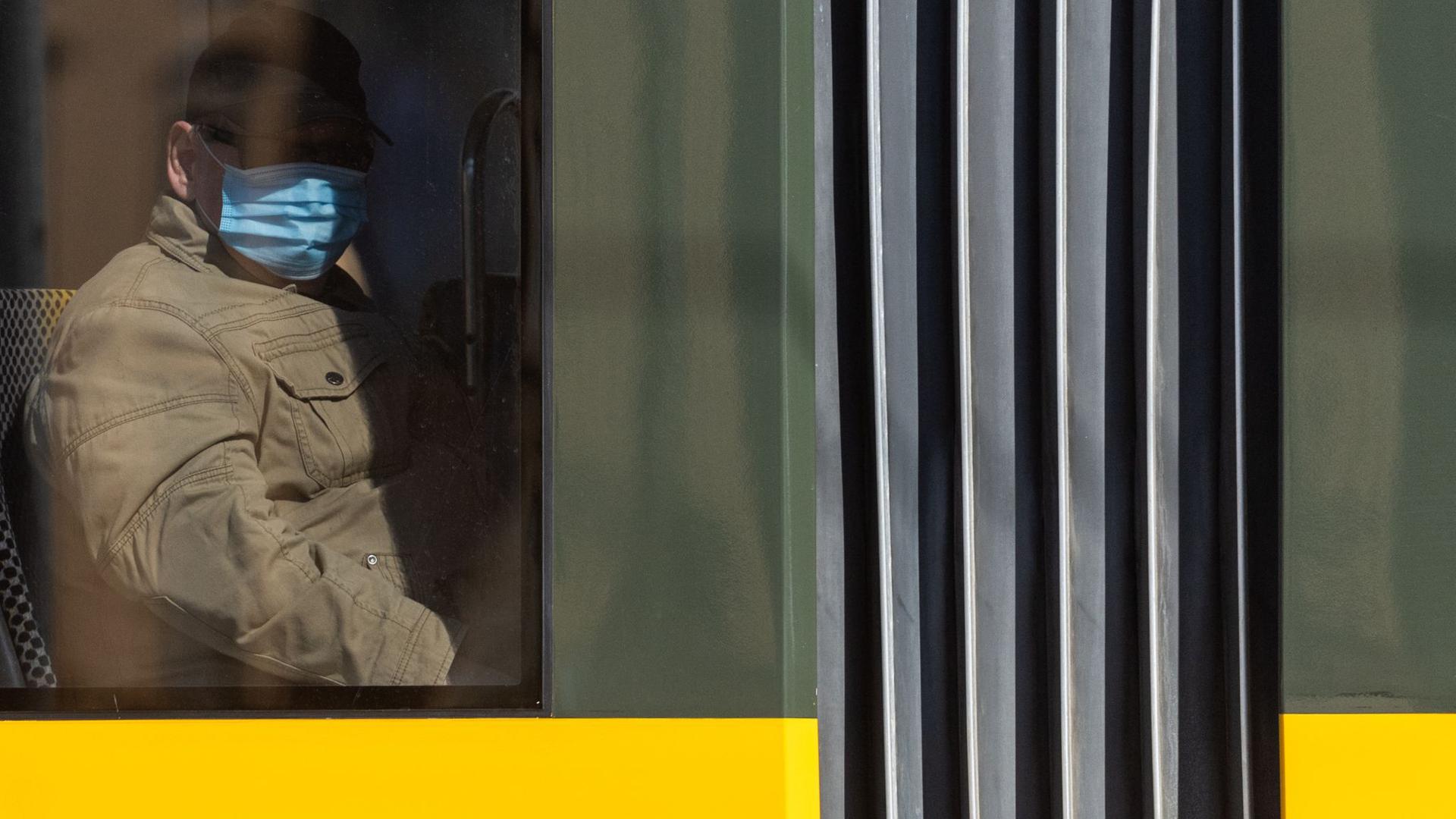 Ein Mann sitzt in der Straßenbahn und trägt einen Mundschutz.