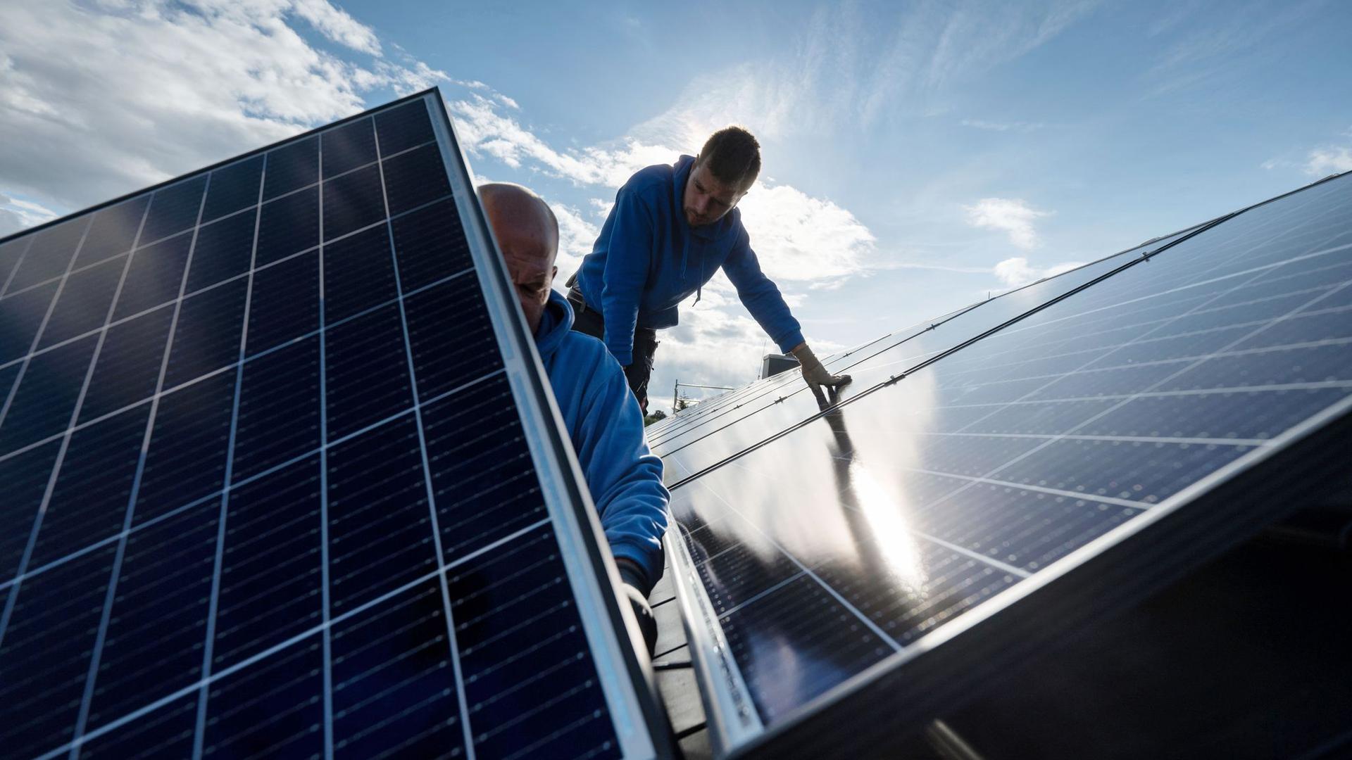 Mitarbeiter der Firma Sontec GmbH montieren Photovoltaikmodule auf dem Dach eines Wohnhauses.