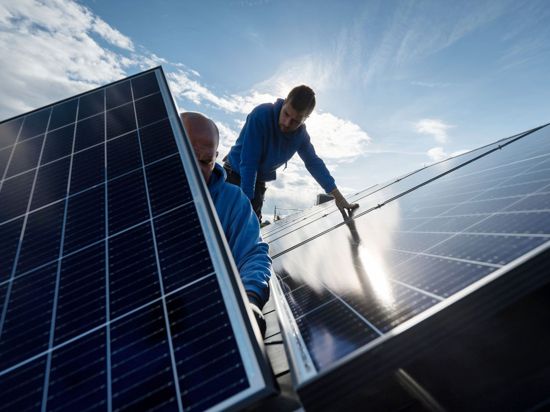 Mitarbeiter der Firma Sontec GmbH montieren Photovoltaikmodule auf dem Dach eines Wohnhauses.