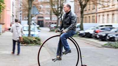 Tobias Krieger fährt mit einem Hochrad eine Straße entlang.
