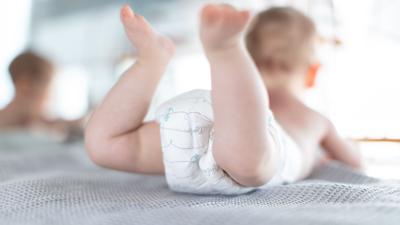 Ein Säugling trägt eine Windel, während er auf einer Kommode liegt.