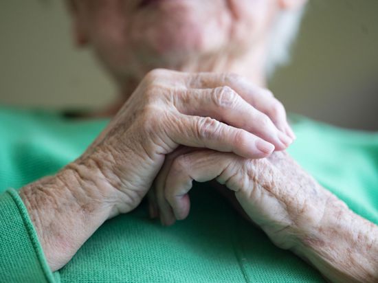 Eine Seniorin faltet ihre Hände.
