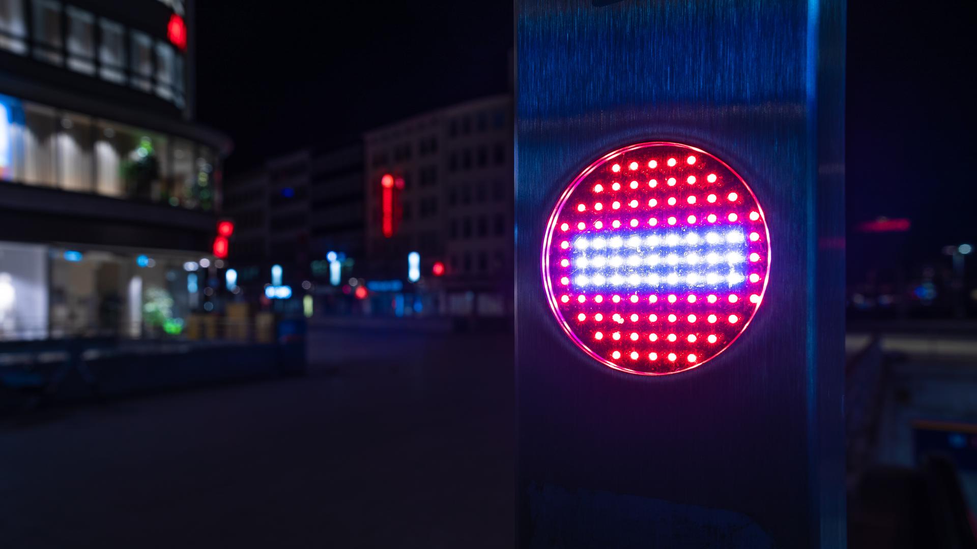 Ein Stop-Piktogramm an einer Rolltreppe leuchtet am späten Abend.