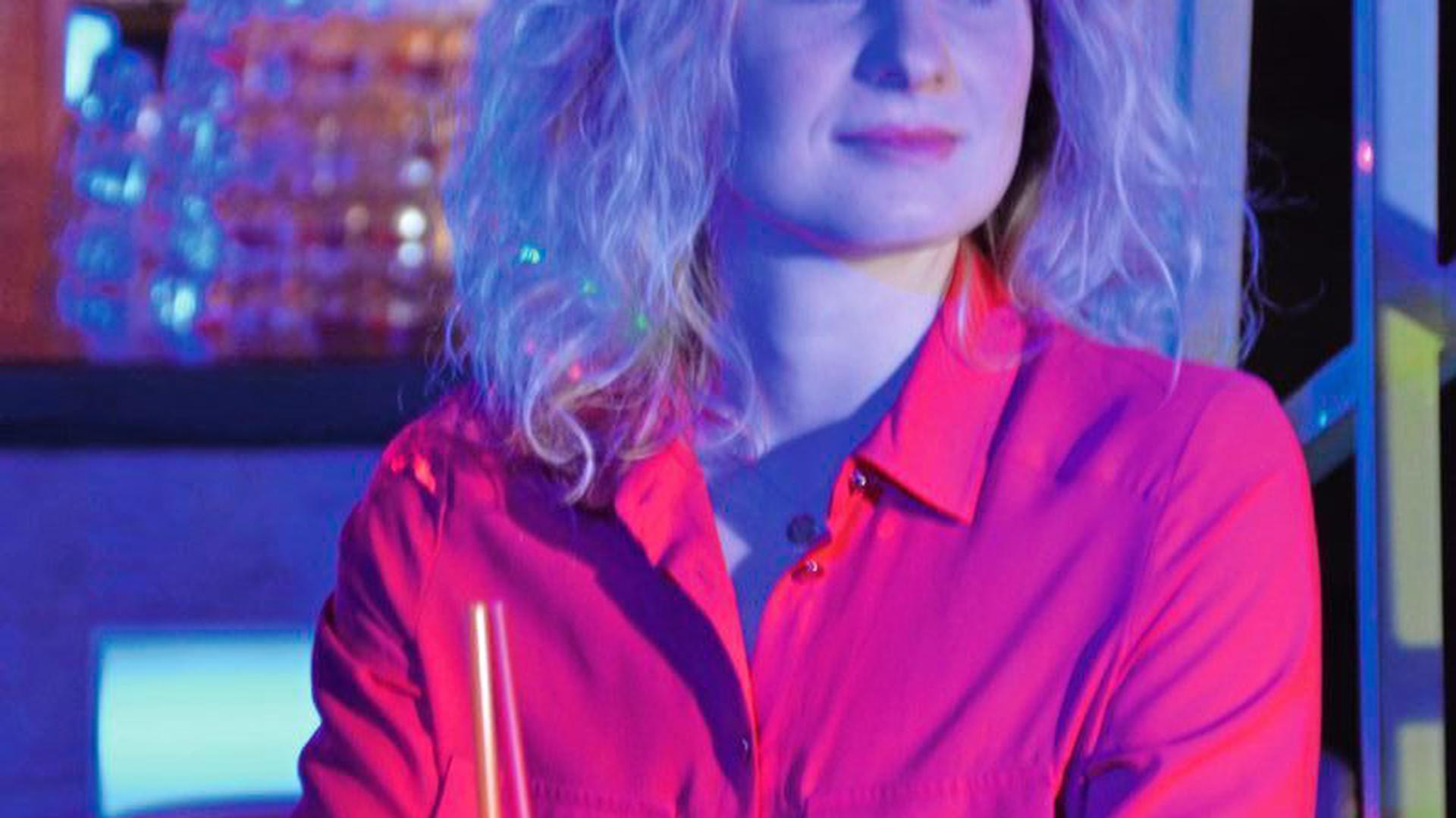 Kim Eisenmann mit einem Cocktail und dem Armband in einer Bar.