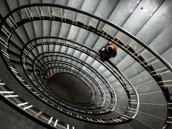 Eine Frau steht in einem Treppenhaus in Hannover, das spiralenförmig nach unten führt.