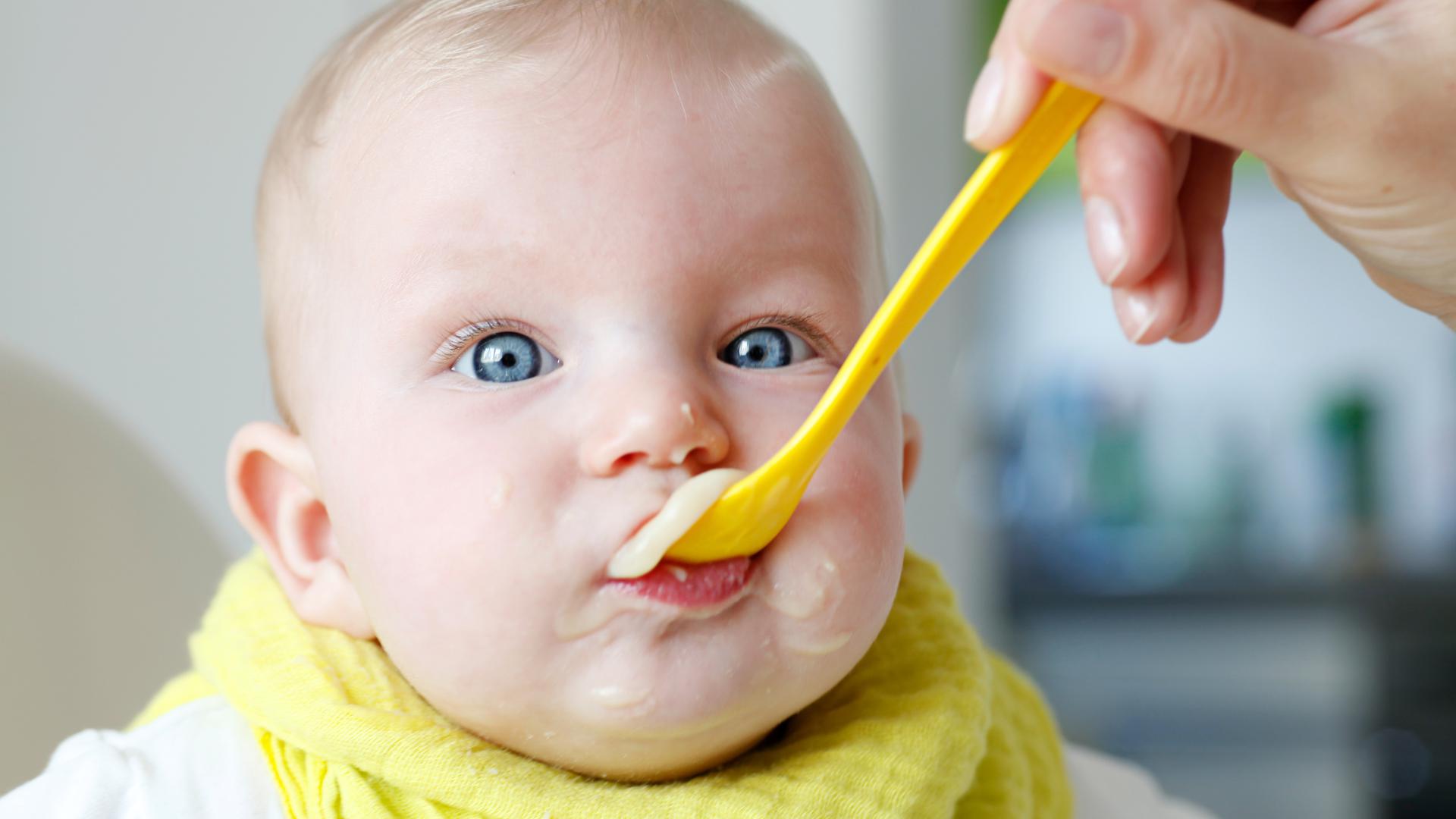 Ein Baby wird mit einem Löffel Brei gefüttert.