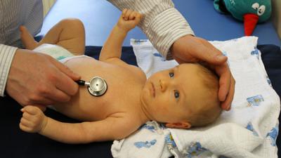 Ein Kinderarzt hört ein Baby ab.