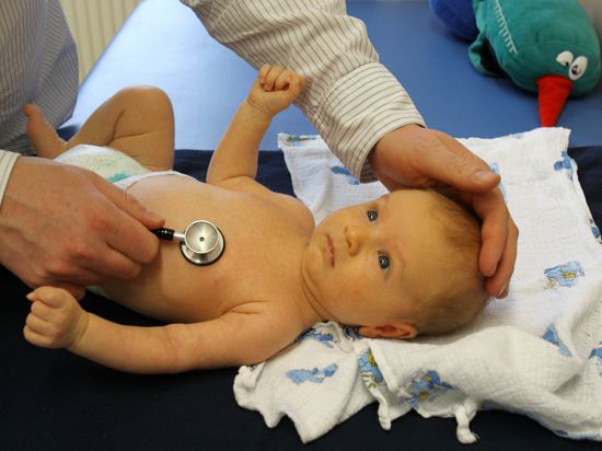 Ein Kinderarzt hört ein Baby ab.