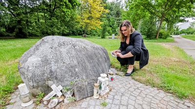 Frau bei großem Stein auf Friedhof