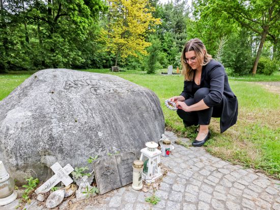 Frau bei großem Stein auf Friedhof