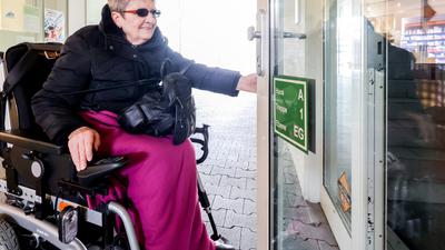 Frau im Rollstuhl versucht, Tür zu öffnen