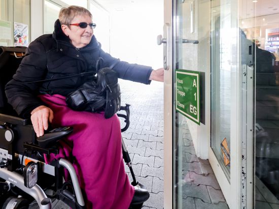 Frau im Rollstuhl versucht, Tür zu öffnen