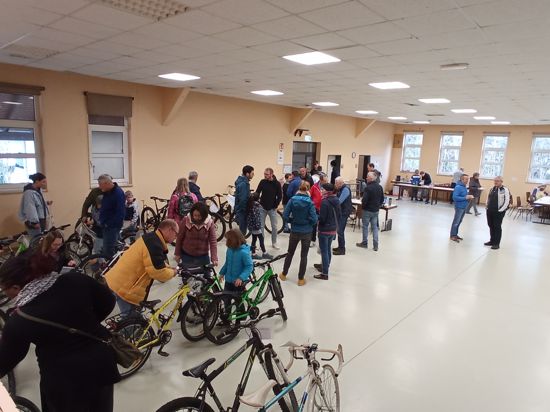 In einer Halle stehen Menschen und Fahrräder.