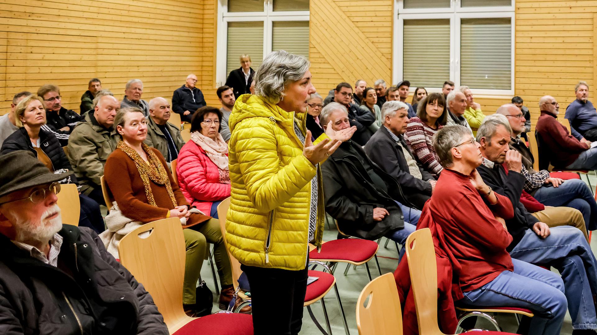 Eine Frau in gelber Jacke steht inmitten eines Auditoriums bei einer Veranstaltung in Dürrenbüchig.