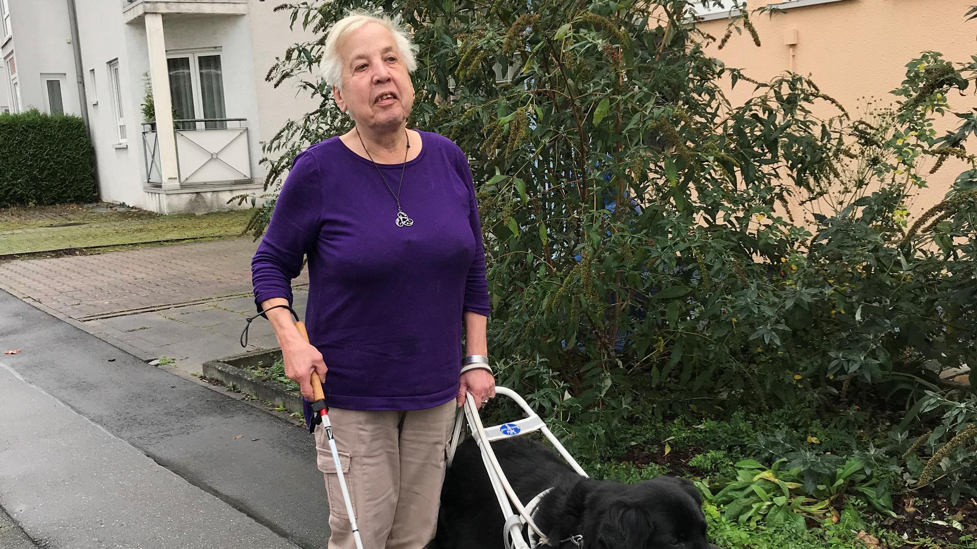 Eine blinde Seniorin mit ihrer zottelig-schwarzen Hundedame, einem Flat Coated Retriever.