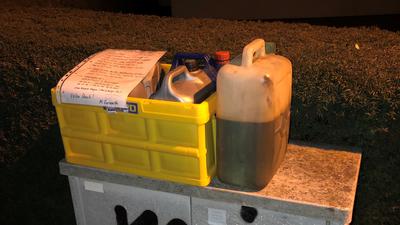Altöl-Kanister in einer Kiste auf einem Stromkasten