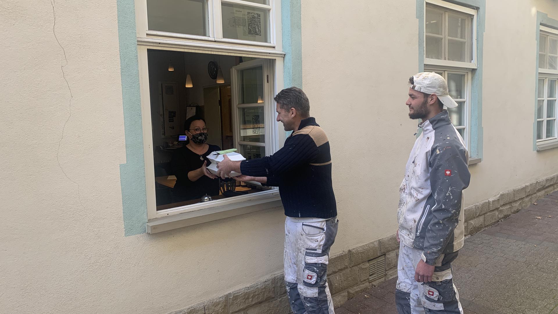 Nadja Oberdorfer (links) gibt zwei bestellte Essen durchs Fenster an die Kunden aus.
