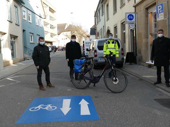 Vier Personen und ein Fahrrad auf der Straße.