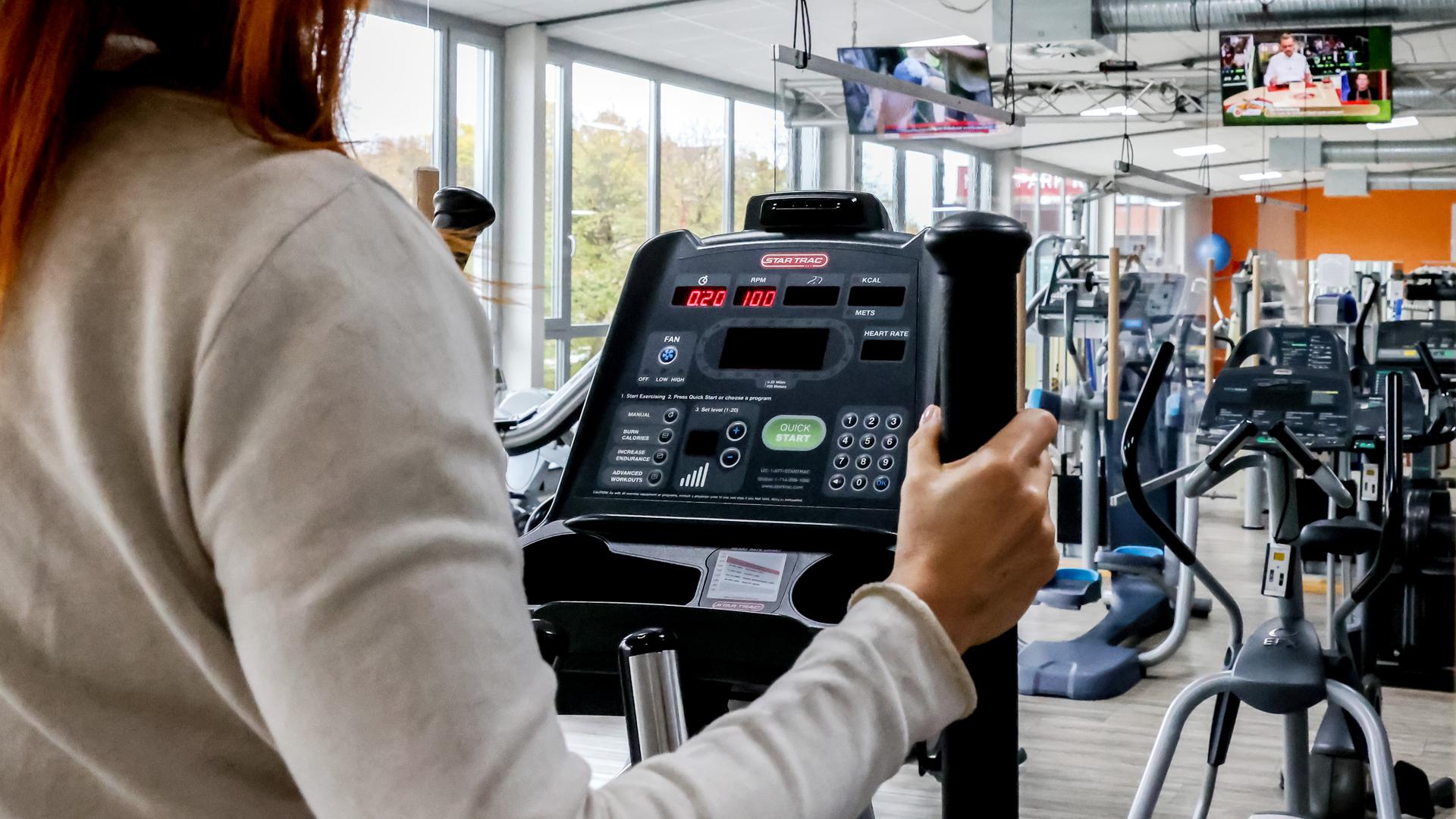 Das Bild zeigt einen Blick in das Fitness-Studio Brüssel`s Instandhaltung Mensch in Bretten. Eine Frau trainiert an einem Crosstrainer. Auch die verrauchen derzeit teuren Strom.