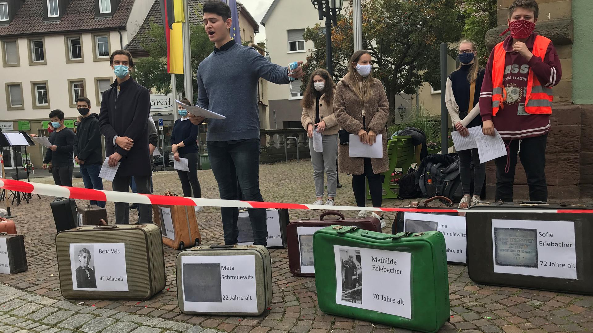 Junger Leute mit Koffern mit Namen und Bildern der Verschleppten
