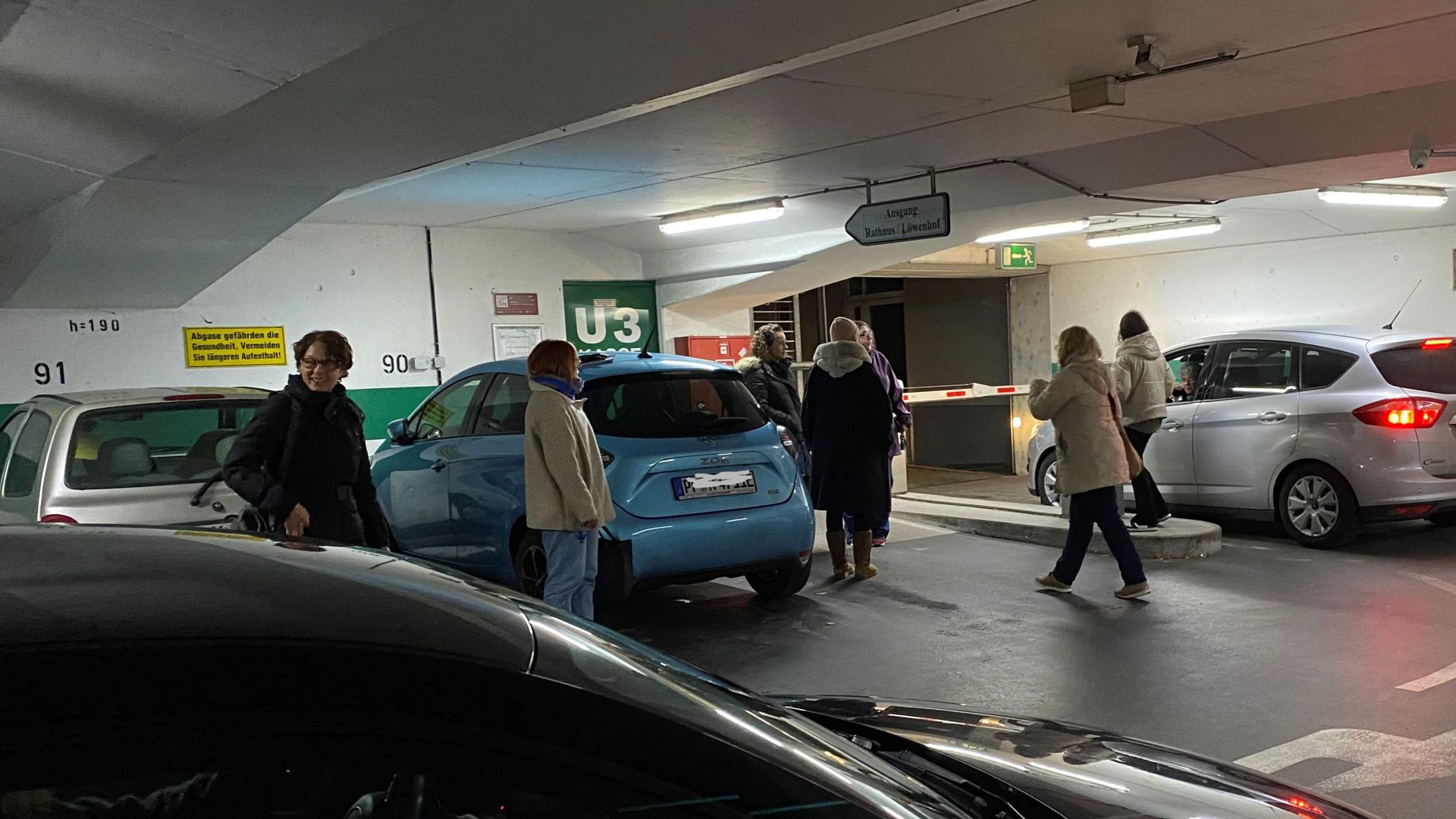 Mehrere Personen stehen in der Tiefgarage und warten auf einen NOtdienst, der sie durch die Schranke hinausfahren lässt. Ein Server-Ausfall hat alle Garagen und Parkplätze der Stadtwerke lahmgelegt.