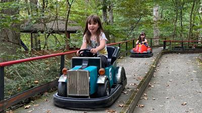 Zwei Mädchen sitzen in zwei kleinen Autos im Märchenwald Kürnbach.