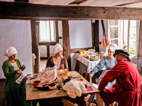 Drei mittelalterlich gewandete Frauen und ein Mann sitzen in historischem Ambiente des Gerbermuseums in Bretten. 