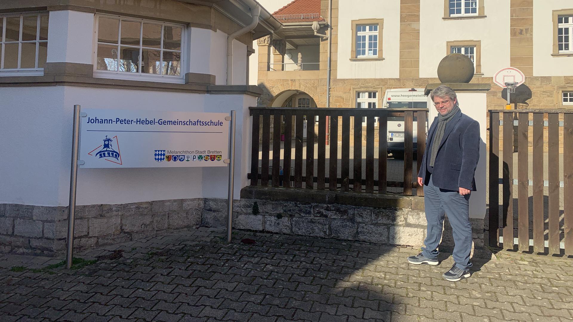SPD-Kandidat Stephan Walter steht neben dem Schild der Brettener Hebel-Schule.