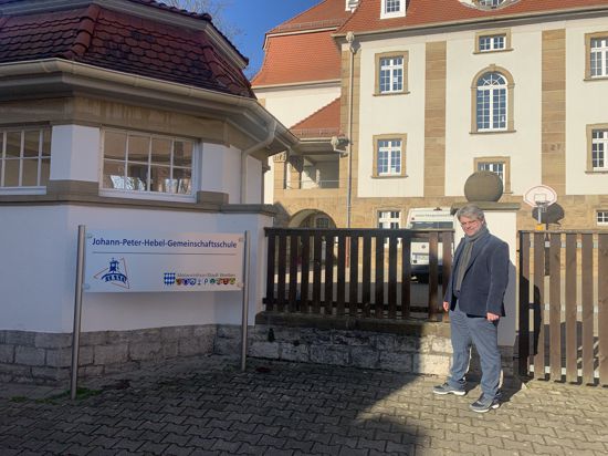 SPD-Kandidat Stephan Walter steht neben dem Schild der Brettener Hebel-Schule.
