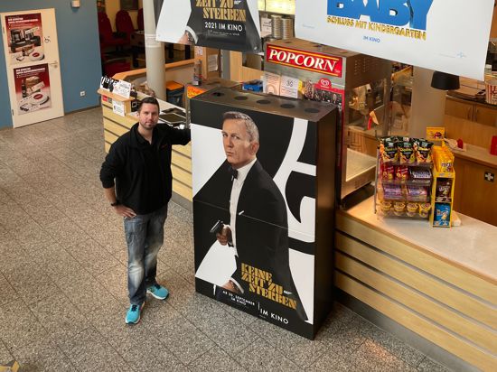 Theaterleiter Lars Skoda steht mit einem Bond-Aufsteller im Foyer des Kinos in Bretten.