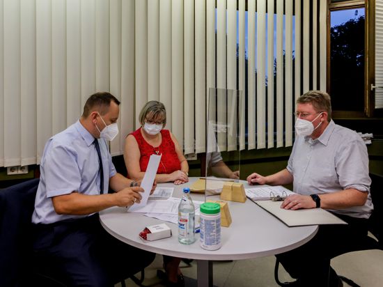 Wahlleiter Simon Bolg (links) und Diana Kern (Mitte) prüfen die Wahlergebnisse aus Dürrenbüchig von Frank Kremser (rechts).