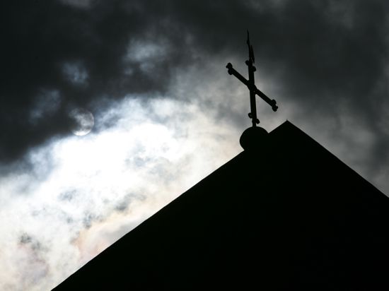 Ein Kirchturm mit dunklen Wolken im Hintergrund.