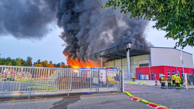 Einsatzkräfte begutachten Flammen und eine hohe Rauchsäule, die aus einem Recyclinghof in Oberderdingen-Flehingen emporsteigen.