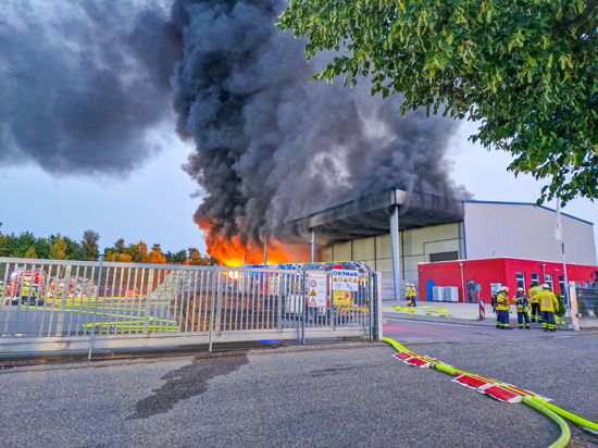 Einsatzkräfte begutachten Flammen und eine hohe Rauchsäule, die aus einem Recyclinghof in Oberderdingen-Flehingen emporsteigen.