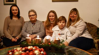 Vier Frauen und ein junge sitzen auf einer Couch. Auf dem Tisch steht ein Adventskranz mit vier brennenden Kerzen.