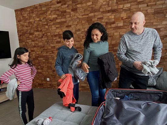 Ein Elternpaar und zwei Kinder packen die Koffer für ein Ostercamp für Familien mit krebskranken Mitgliedern.