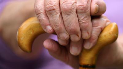 Hand eines älteren Menschen an einem Gehstock