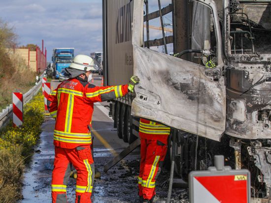 Zwei Einsatzkräfte inspizieren das verbrannte Fahrerhaus des Lastwagens. 