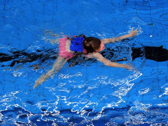Ein Mädchen mit Schwimmhilfen im Becken einer Schwimmhalle, Symbolbild Schwimmkurs