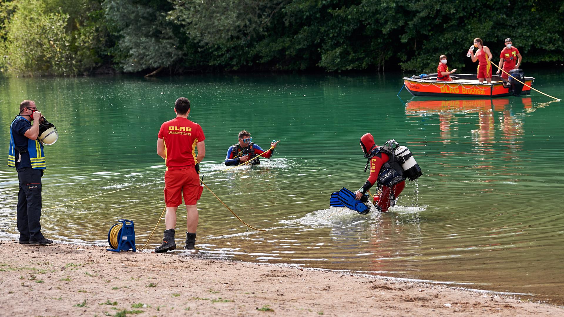 Einsatzkräfte des DLRG suchen am Baggersee Untergrombach mit Booten und Tauchern nach einem vermissten Mann.