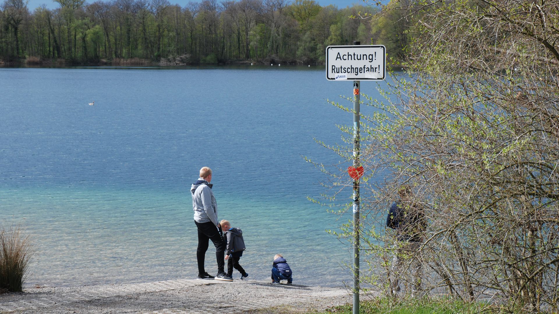 Eine Familie steht am Ufer des Baggersees Untergrombach.